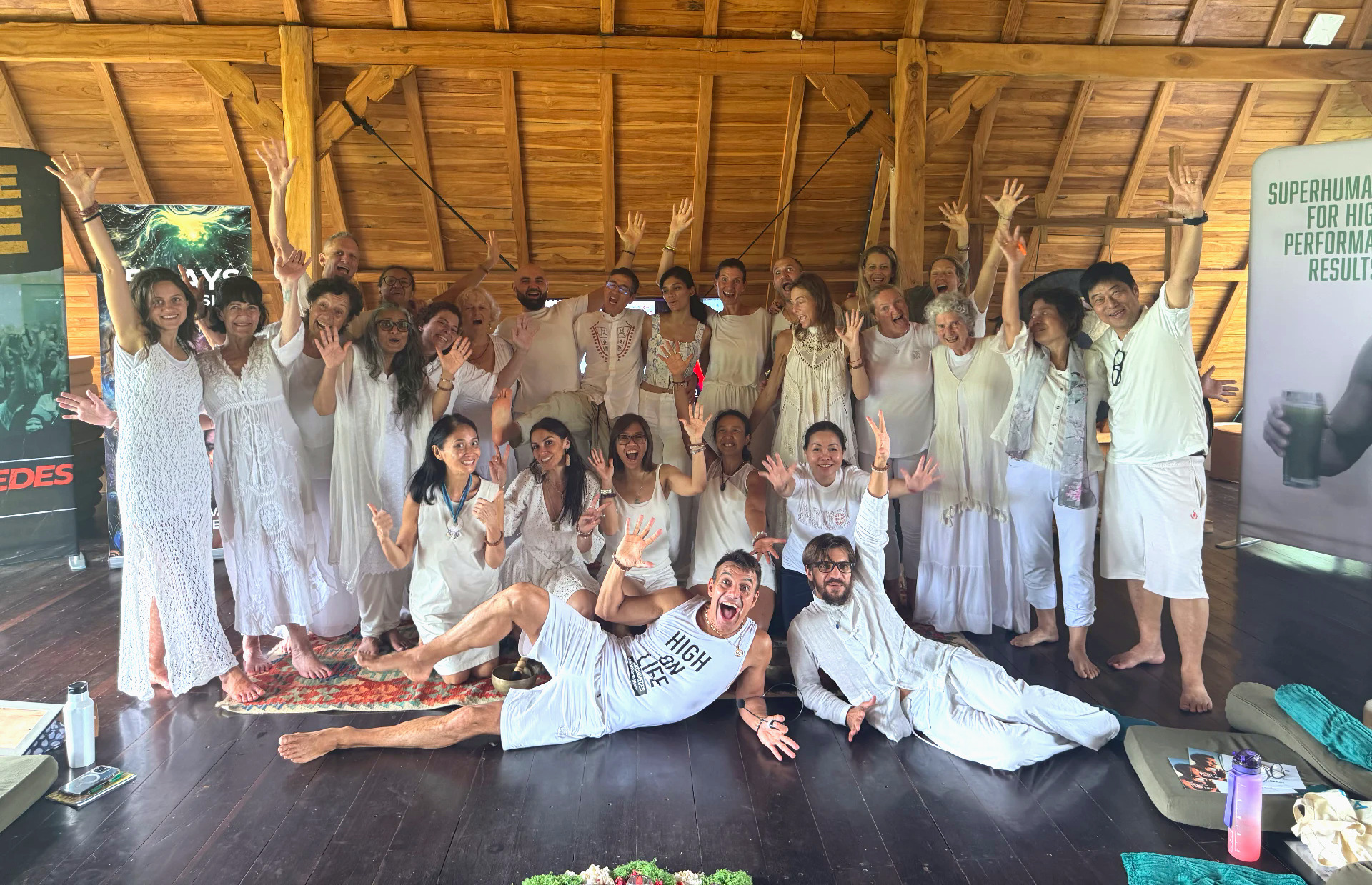 A large group of people dressed in white cheering and laughing together at a wellness retreat